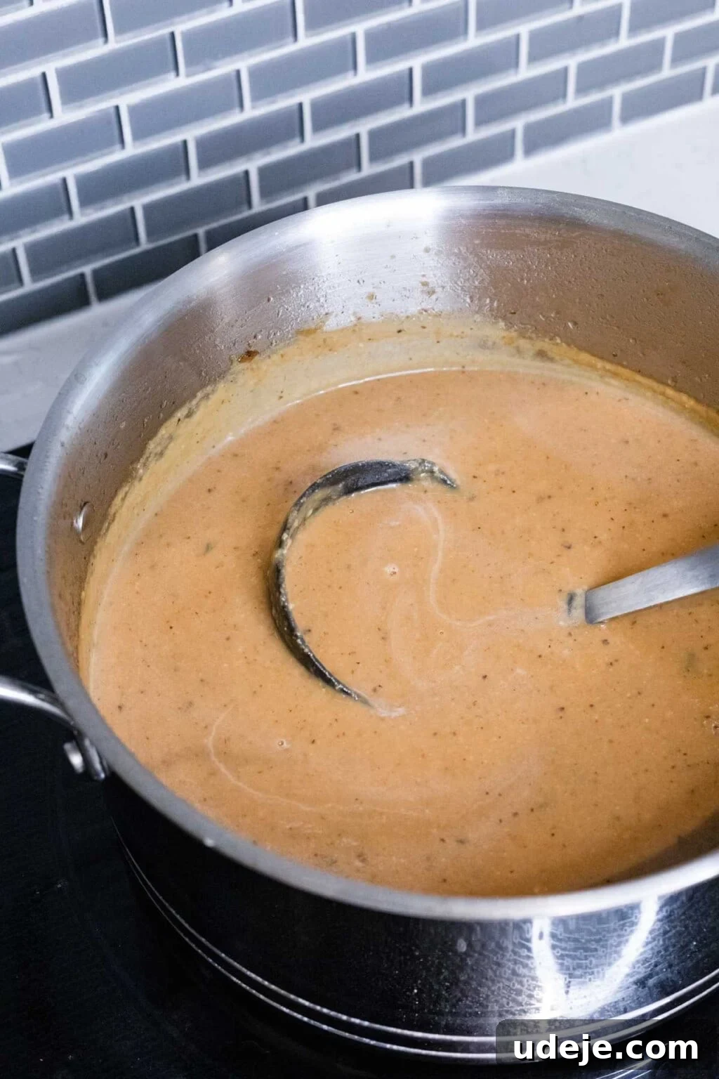 Creamy Cauliflower Soup with Golden Caramelized Onions 5 Blended cauliflower soup in a pot with an immersion blender, showing its smooth, creamy texture
