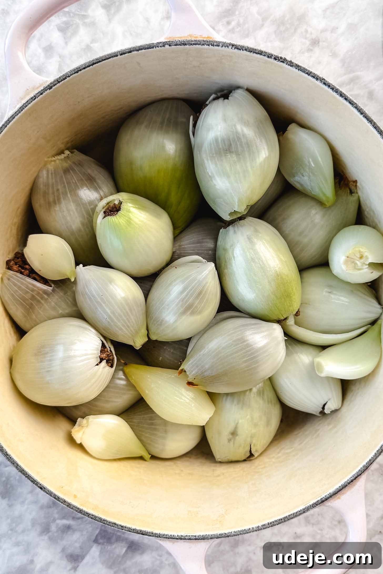 Hearty Beef-Stuffed Onions 12 Stuffed onion layers in a white pot on a marble background.