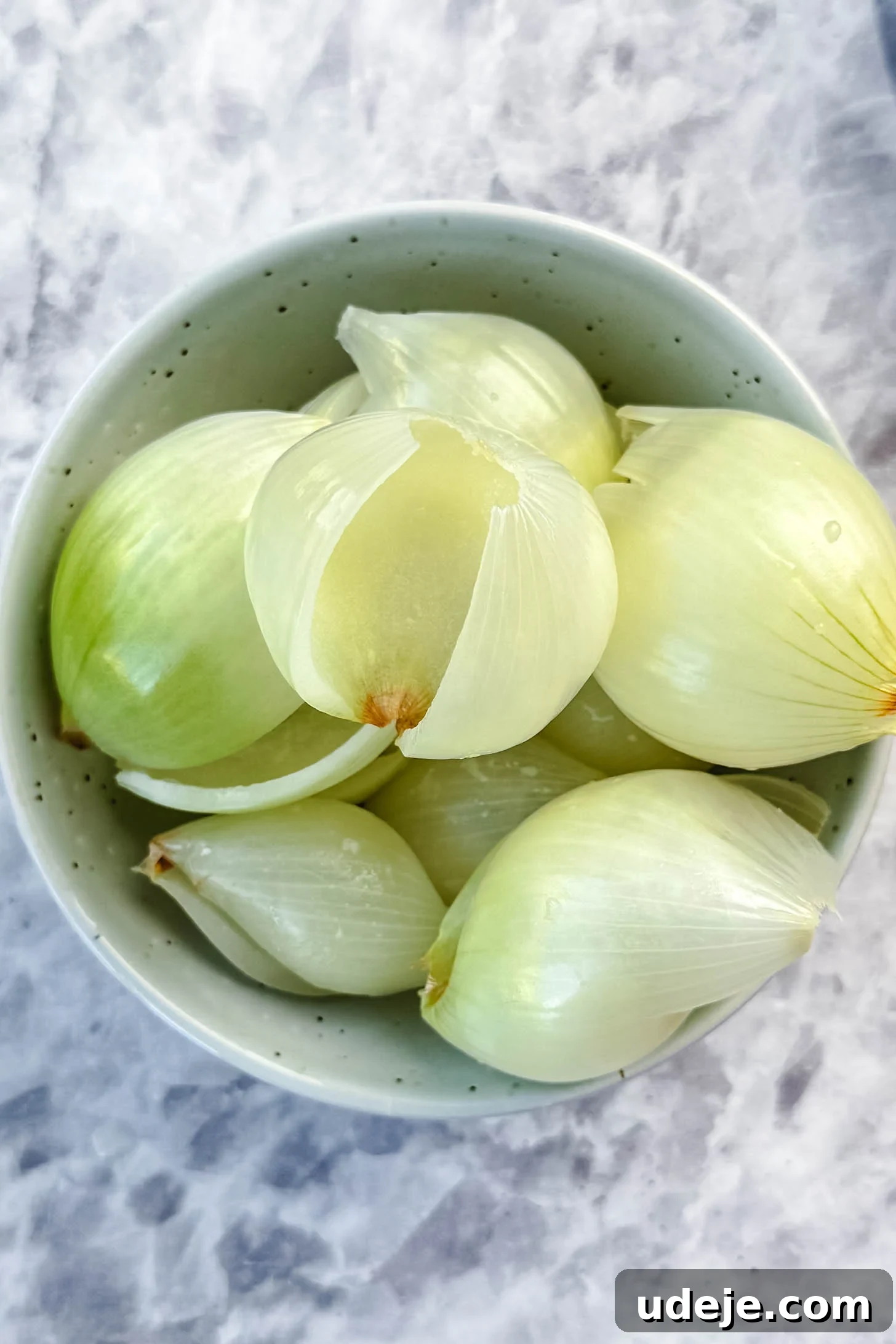 Hearty Beef-Stuffed Onions 9 Layers of onion in a blue speckled bowl on a marble background.