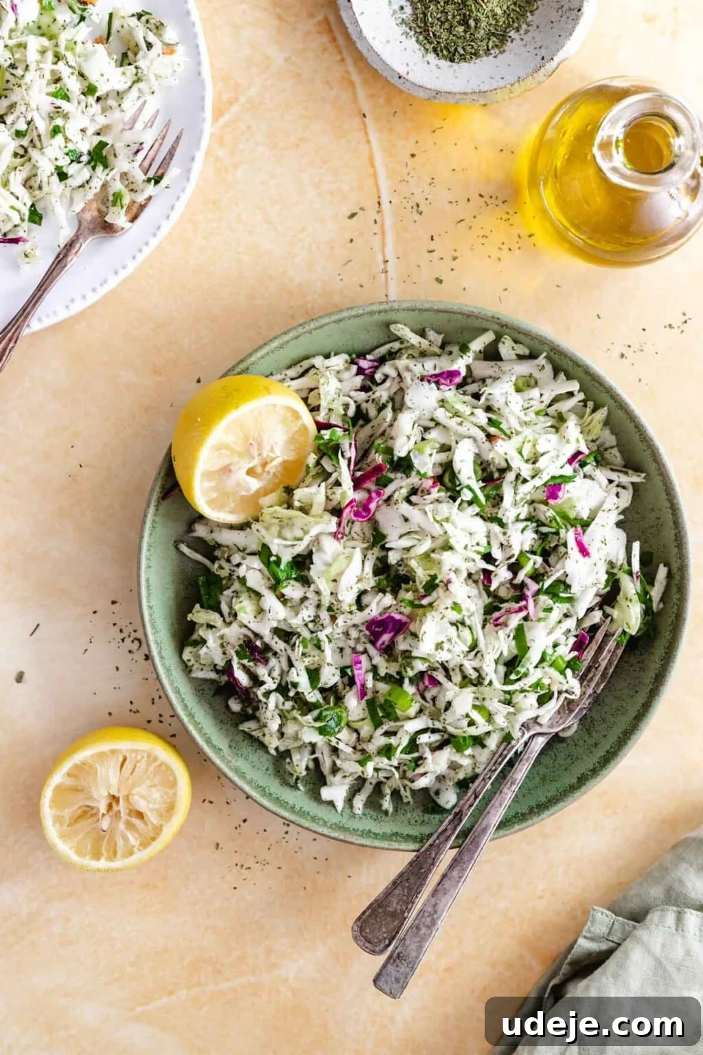 Refreshing Lebanese Cabbage Salad 2 Malfouf salad served in a green plate with lemons and cutlery, showcasing its fresh and inviting appearance.