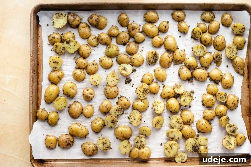 Perfectly Crispy Roasted Potatoes 4 Seasoned baby potatoes, cut in half, arranged on a baking sheet lined with parchment paper, ready for roasting.