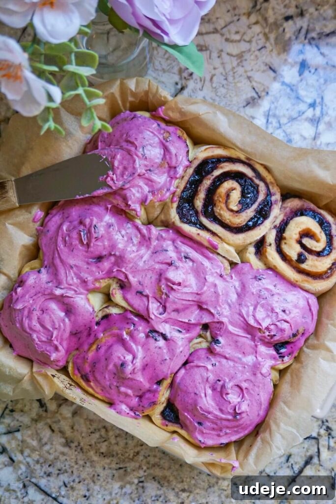 Plant-Based Blueberry Morning Buns 2 Delicious Vegan Blueberry Rolls, swirled with homemade blueberry jam and generously topped with a smooth blueberry cream cheese frosting, perfect for any occasion.