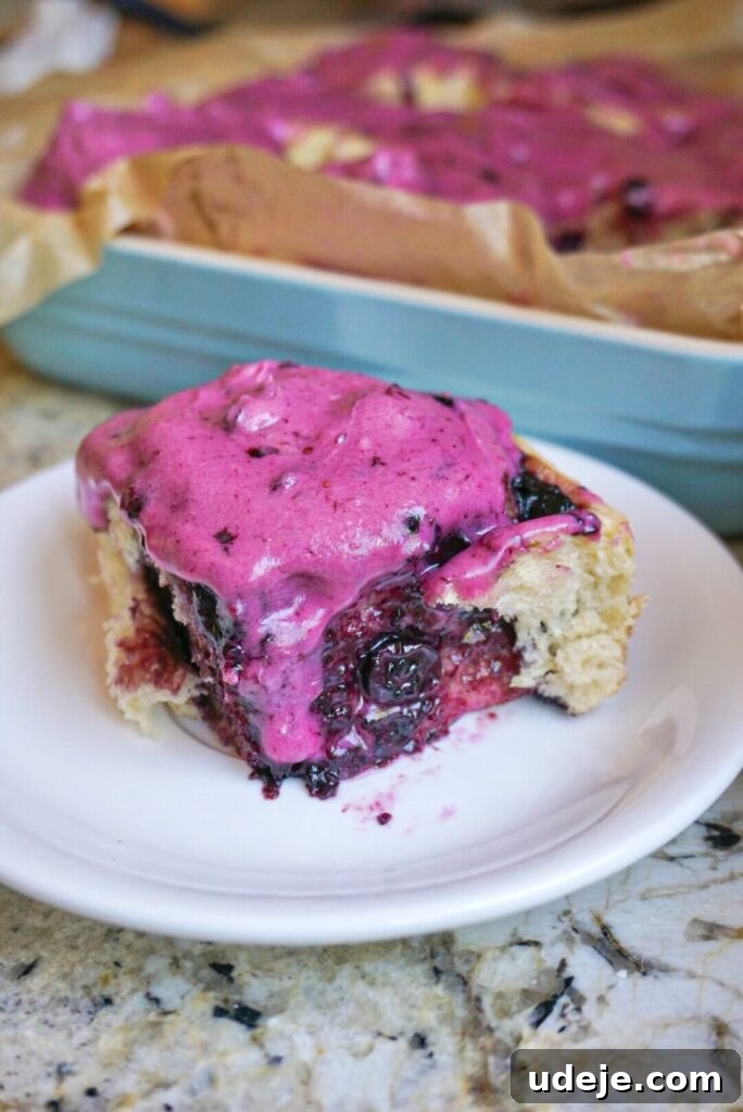 Plant-Based Blueberry Morning Buns 3 Close-up of fluffy Vegan Blueberry Rolls with vibrant purple frosting, showcasing the homemade jam swirls.