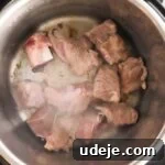 Effortless Green Bean Stew Instant Pot and Stovetop 16 veal cubes browning in an Instant Pot on a light marble background