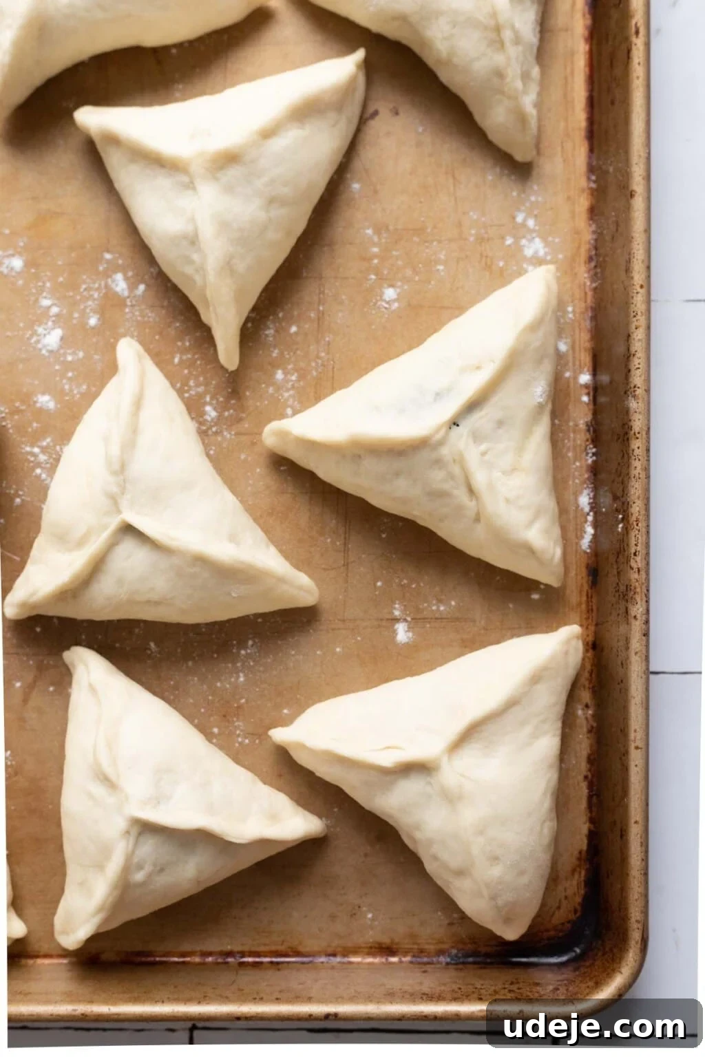 Authentic Homemade Spinach and Cheese Fatayer 13 Unbaked spinach fatayer on a brown baking sheet