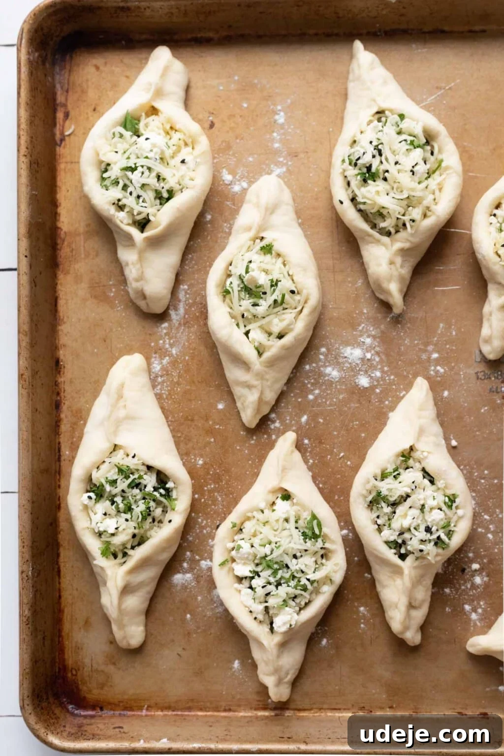 Authentic Homemade Spinach and Cheese Fatayer 14 Unbaked cheese fatayer on a brown baking sheet