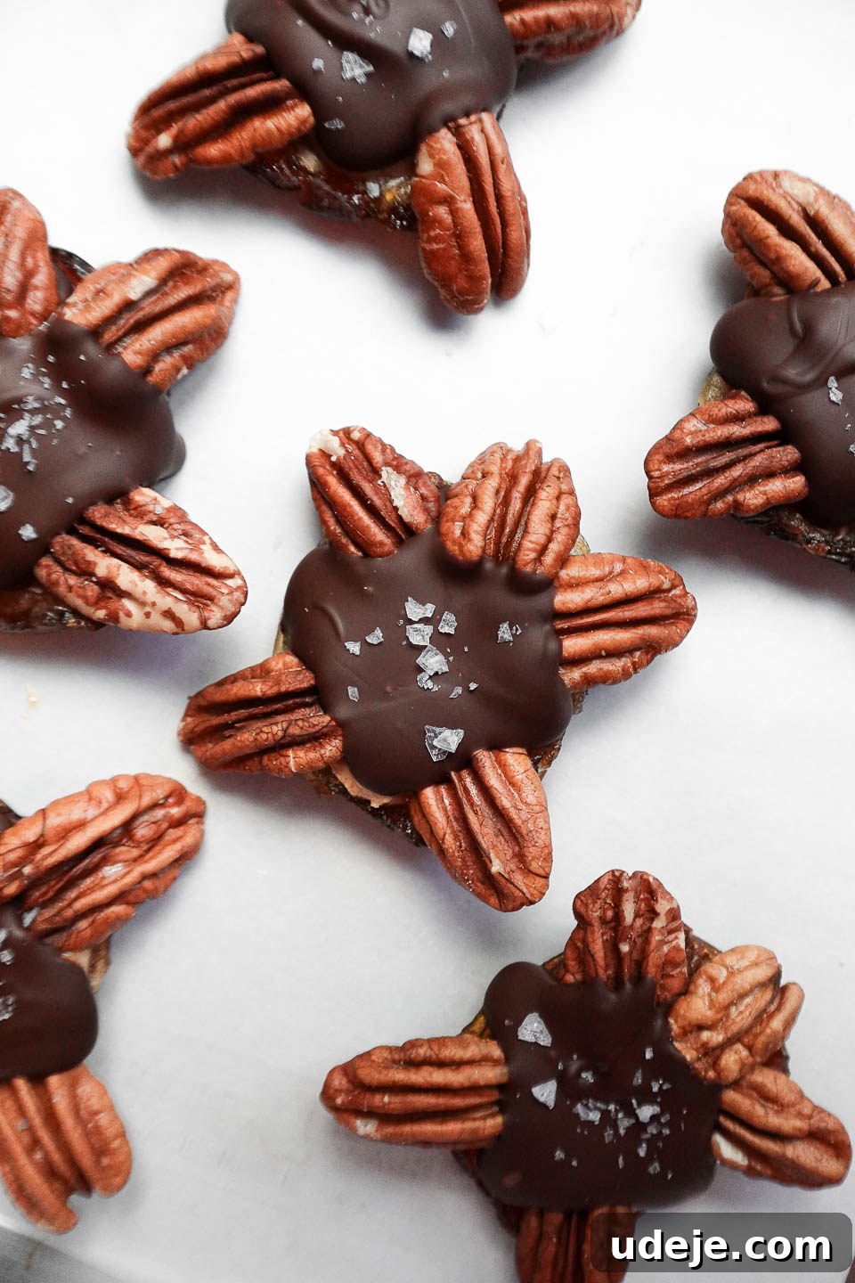Easy 4-Ingredient Healthy Chocolate Turtles 2 A close-up view of finished healthy chocolate turtles, made with dates, pecans, peanut butter, and dairy-free chocolate, neatly arranged on a baking sheet, ready to be enjoyed.