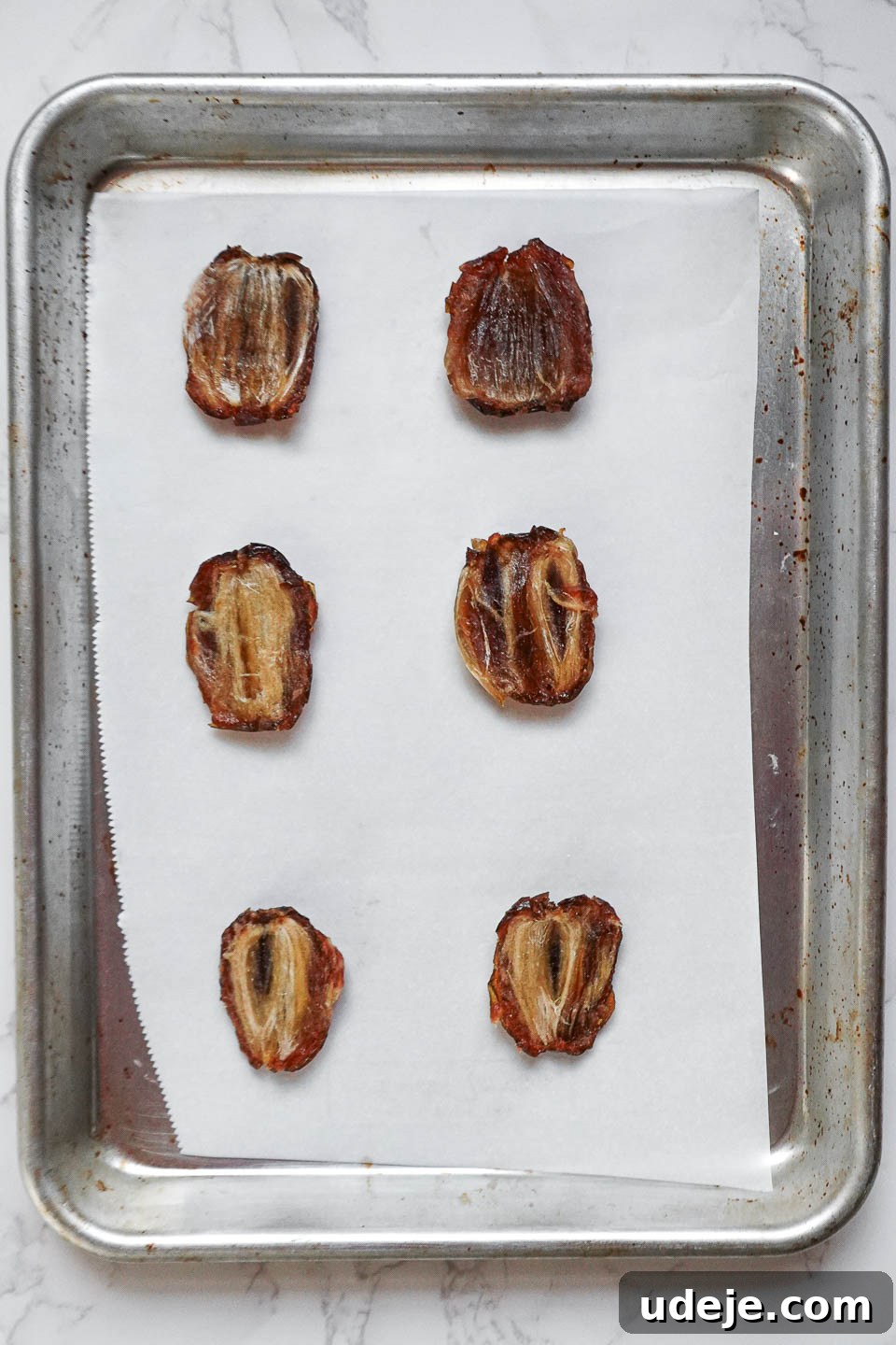 Easy 4-Ingredient Healthy Chocolate Turtles 5 Sliced Medjool dates with pits removed, arranged neatly on a parchment-lined tray, showcasing their readiness for the next step of assembling healthy chocolate turtles.