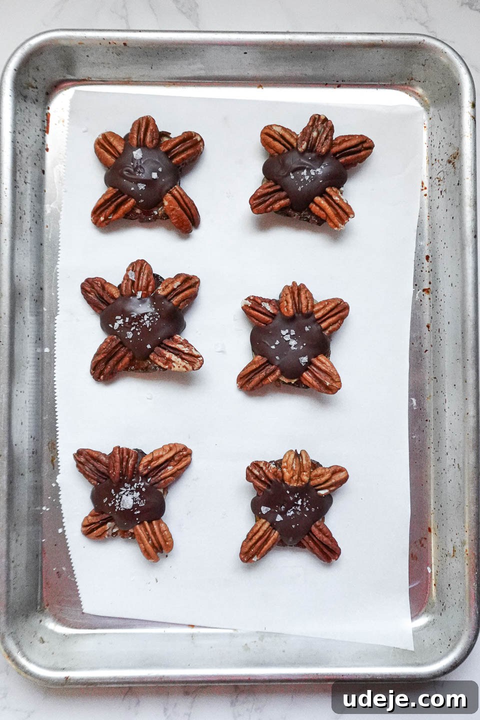 Easy 4-Ingredient Healthy Chocolate Turtles 7 A close-up view of vegan chocolate turtles on a tray, with their chocolate coating still soft, just moments before being placed in the freezer to set and firm up.