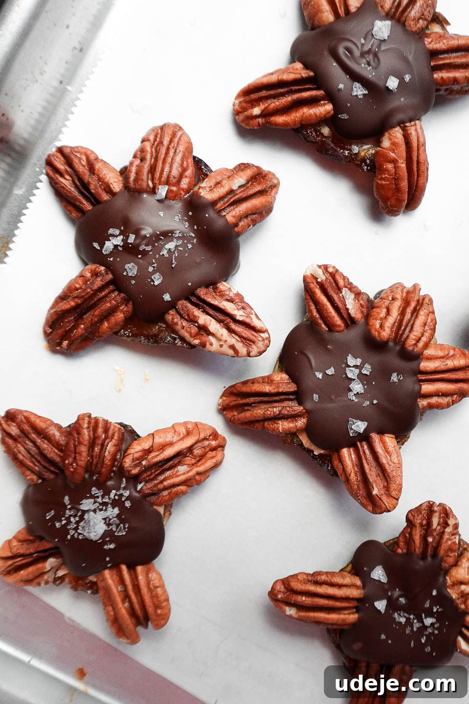 Easy 4-Ingredient Healthy Chocolate Turtles 8 A baking sheet filled with perfectly formed healthy chocolate turtles, made with dates, peanut butter, pecans, and dairy-free chocolate, ready for serving or storage.