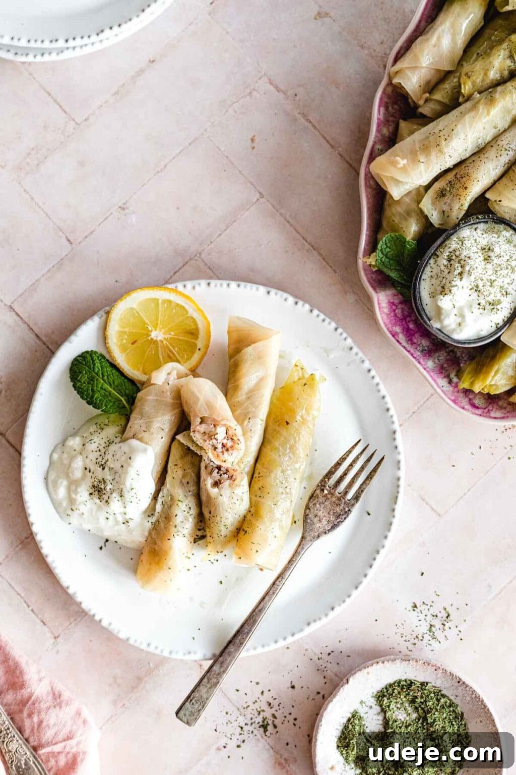Authentic Lebanese Cabbage Rolls 11 stuffed cabbage rolls served on a white plate with a side of yogurt and lemon wedges