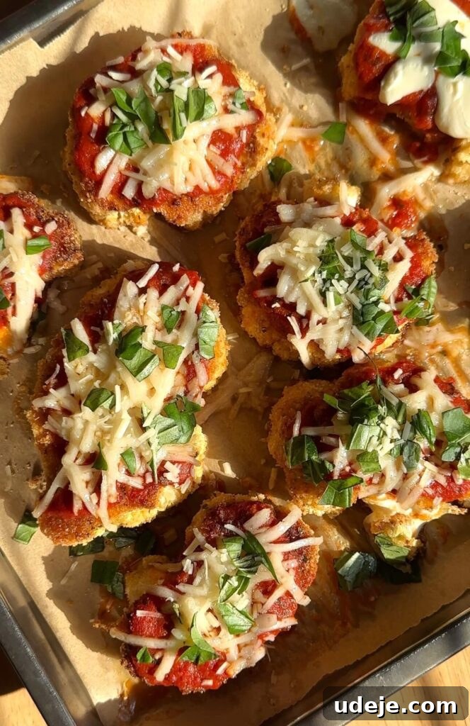 Roasted Cauliflower Parmesan 2 Golden brown vegan cauliflower parmesan steaks topped with melted mozzarella, marinara sauce, and fresh basil, served on a sheet pan for a healthy weeknight meal.