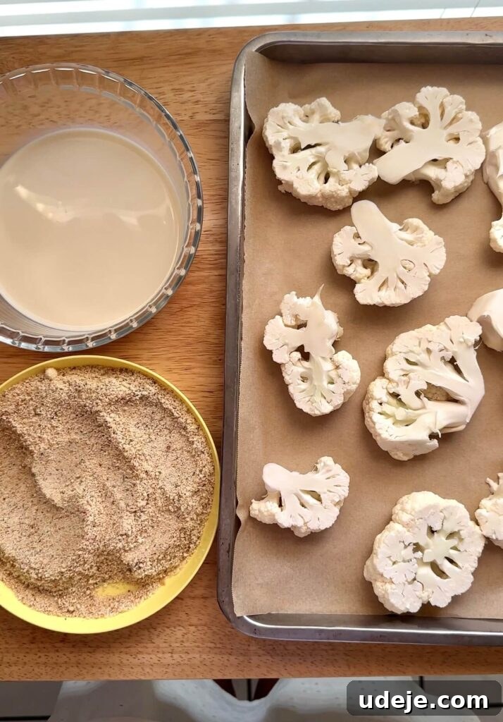 Roasted Cauliflower Parmesan 3 Sliced cauliflower florets being dipped in non-dairy milk as part of the breading process for vegan cauliflower parmesan.
