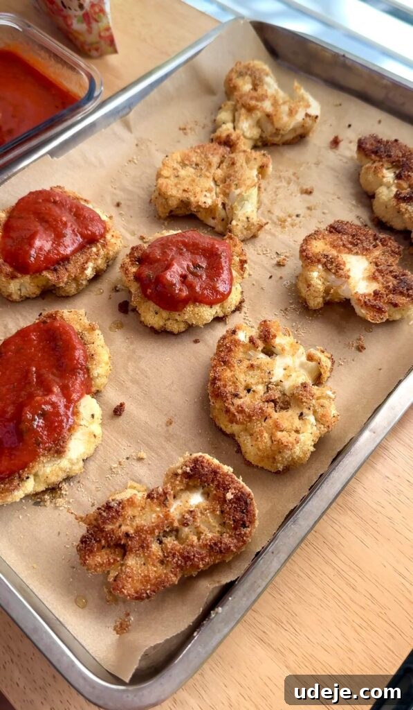 Roasted Cauliflower Parmesan 4 Cauliflower steaks coated in a golden breading mixture of almond flour and gluten-free bread crumbs, ready for baking.