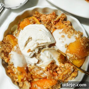 Ramekin with a serving of healthy peach crisp with vegan vanilla ice cream melting on top.