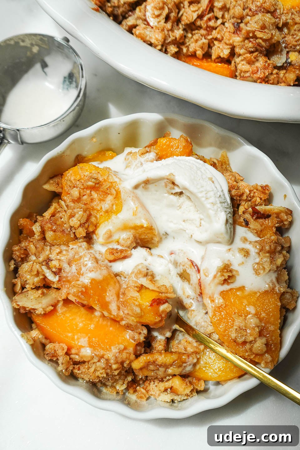 Wholesome Peach Crumble 9 A close-up view of freshly baked peach crisp, showcasing its vibrant flavors, topped with a melting scoop of creamy vegan vanilla ice cream.