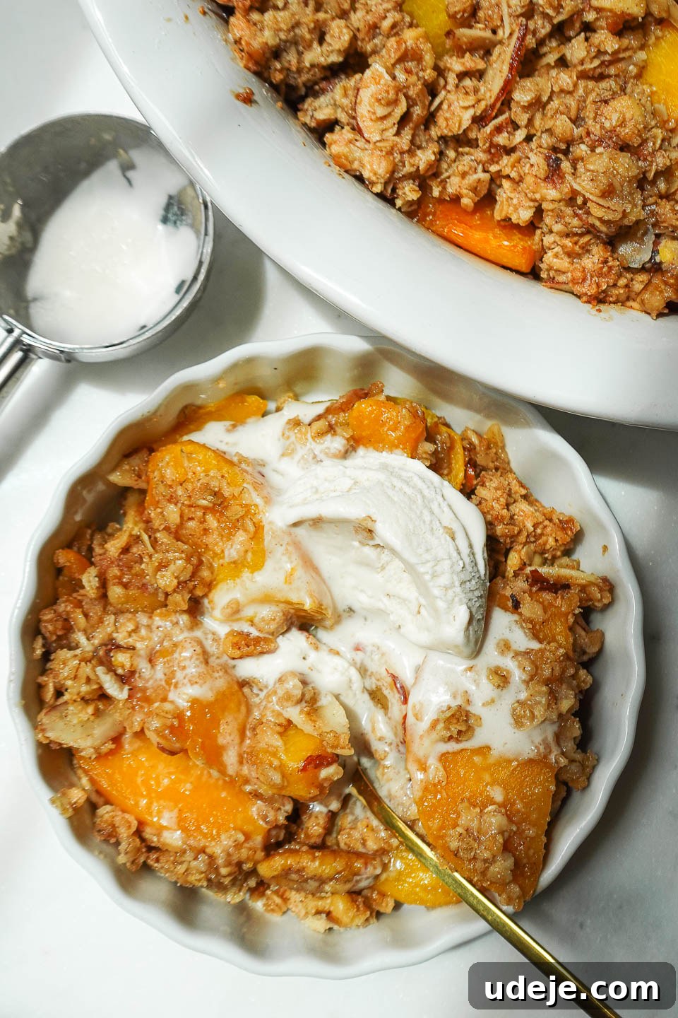Wholesome Peach Crumble 10 An elegant overhead shot of freshly baked peach crisp, topped with a single, perfectly melting scoop of vegan vanilla ice cream, ready to be enjoyed.