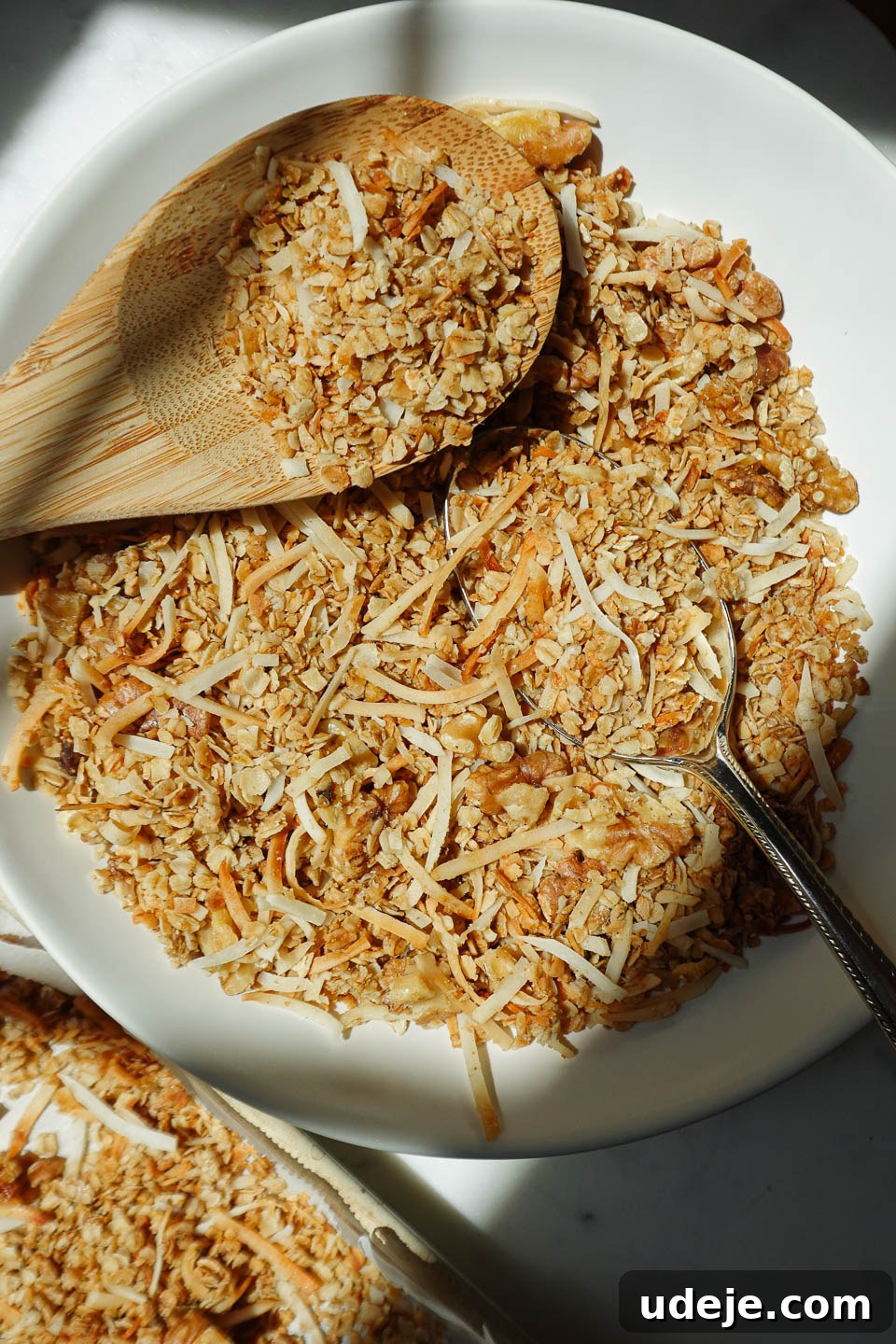 Simply Delicious Five Ingredient Healthy Granola 2 Delicious healthy homemade granola in a rustic bowl with a wooden spoon, highlighting its simple 5-ingredient composition.