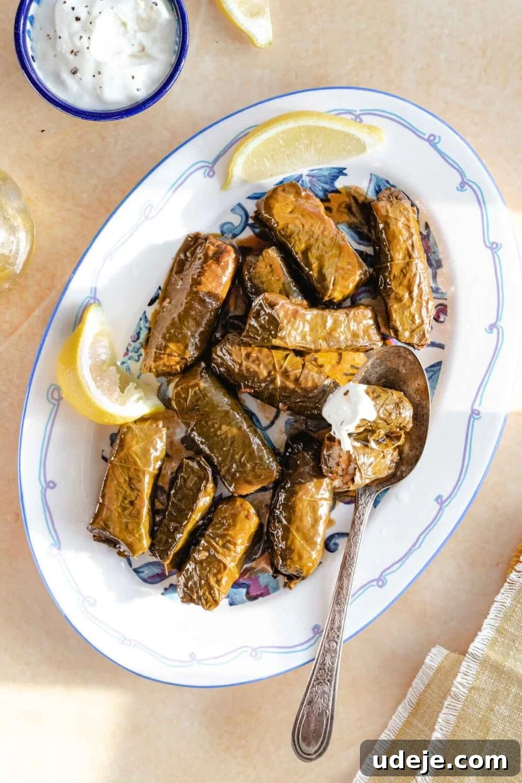 Authentic Yalanji Vegetarian Stuffed Grape Leaves 2 Vegetarian stuffed grape leaves (Yalanji) served on a platter, with one cut open and ready to be dipped in yogurt.