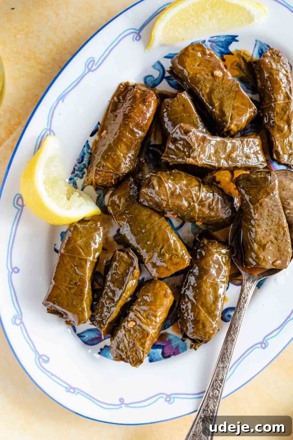 Authentic Yalanji Vegetarian Stuffed Grape Leaves 13 Vegetarian stuffed grape leaves (Yalanji) served on a platter, garnished with fresh lemon wedges for added zest.