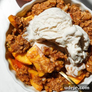 Single serve healthy peach crisp in a white ramekin topped with golden oat-nut crumble