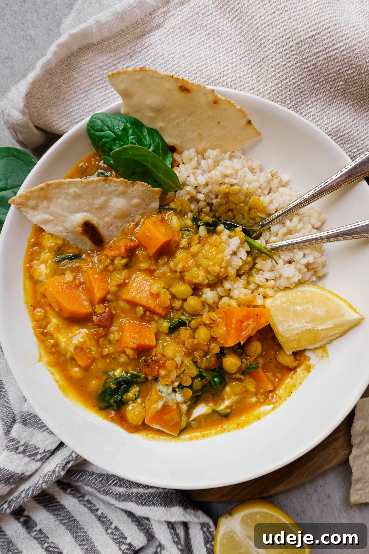 Spiced Chickpea Sweet Potato Lentil Delight 2 Close-up shot of Chickpea, Sweet Potato, and Lentil Curry served with naan, a lemon wedge, and spoons