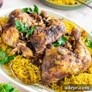 Chicken and rice served on a white platter topped with cilantro, almonds, and raisins, showcasing a decadent Chicken Mandi.