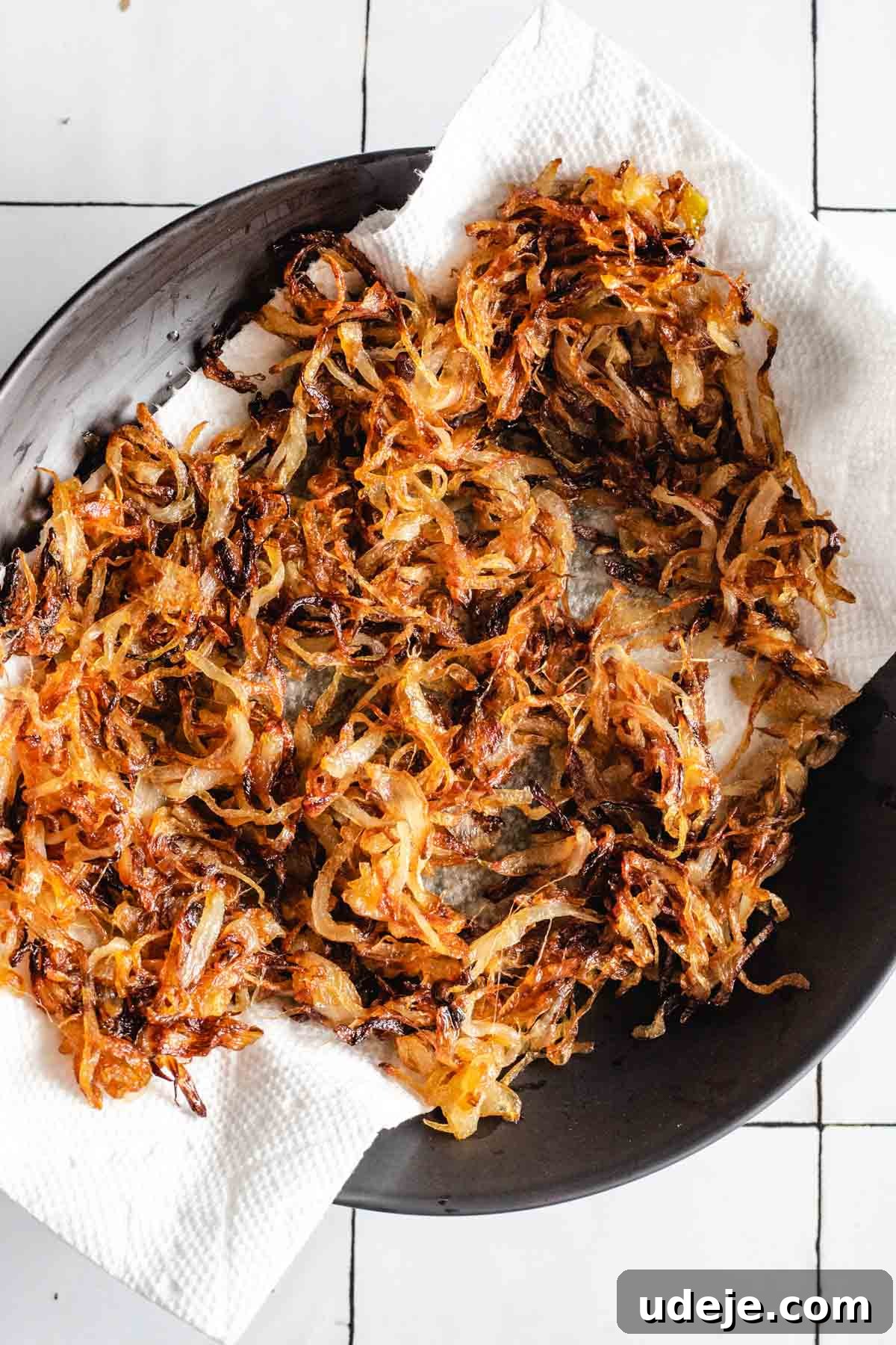 Yemeni Chicken Mandi with Fragrant Spiced Rice 9 A generous layer of perfectly fried onions draining on a paper towel-lined black ceramic plate.