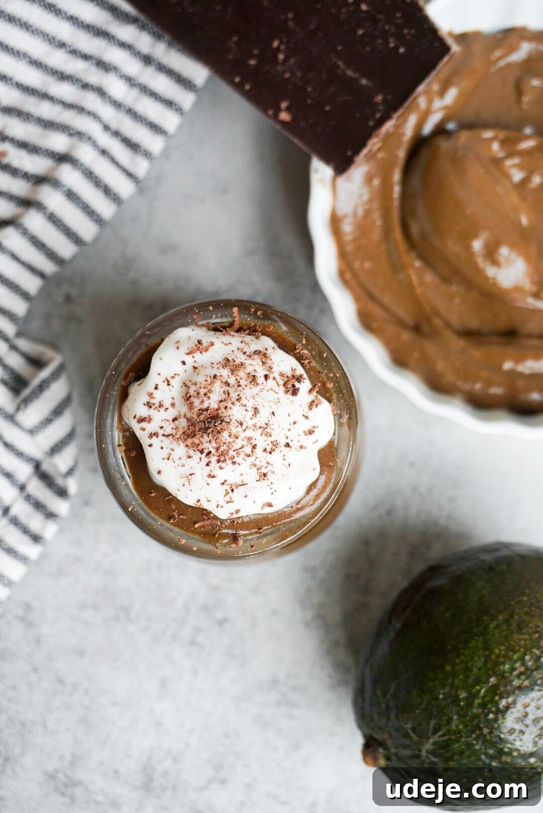 Decadent Chocolate Avocado Mousse 4 Creamy vegan chocolate avocado pudding topped with coconut whipped cream and shaved chocolate in a glass jar.