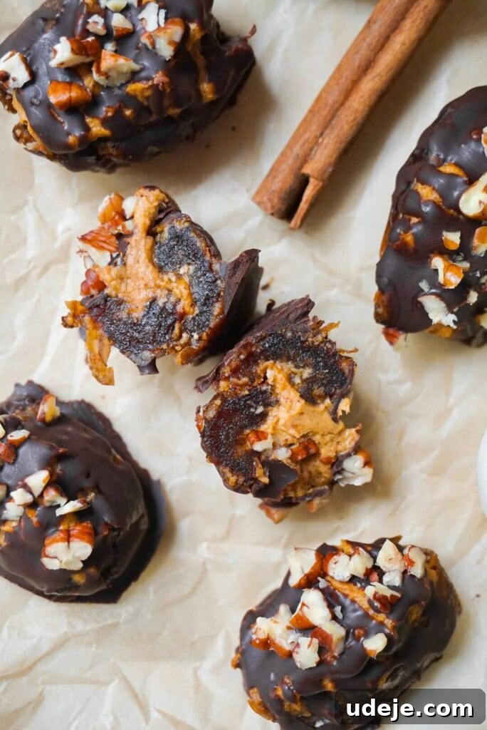Pumpkin Spice Date Poppers 4 Three Pumpkin Stuffed Dates, generously drizzled with melted chocolate and topped with chopped pecans, showcased on a wooden board, ready to be enjoyed.
