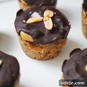 Easy Plant-Based Chocolate Peanut Caramel Cups 5 A finished Snickers Cup, showing its layers of base, caramel, peanuts, and chocolate.