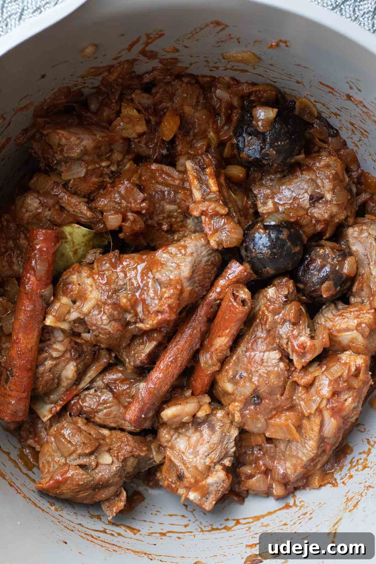 Chef's Signature Lamb Kabsa 7 Chunks of lamb stewed with onions, whole cinnamon sticks, bay leaves, and black olives in a rich tomato-based sauce evoke the aromatic warmth found in lamb kabsa, featuring visible spices and tender meat.