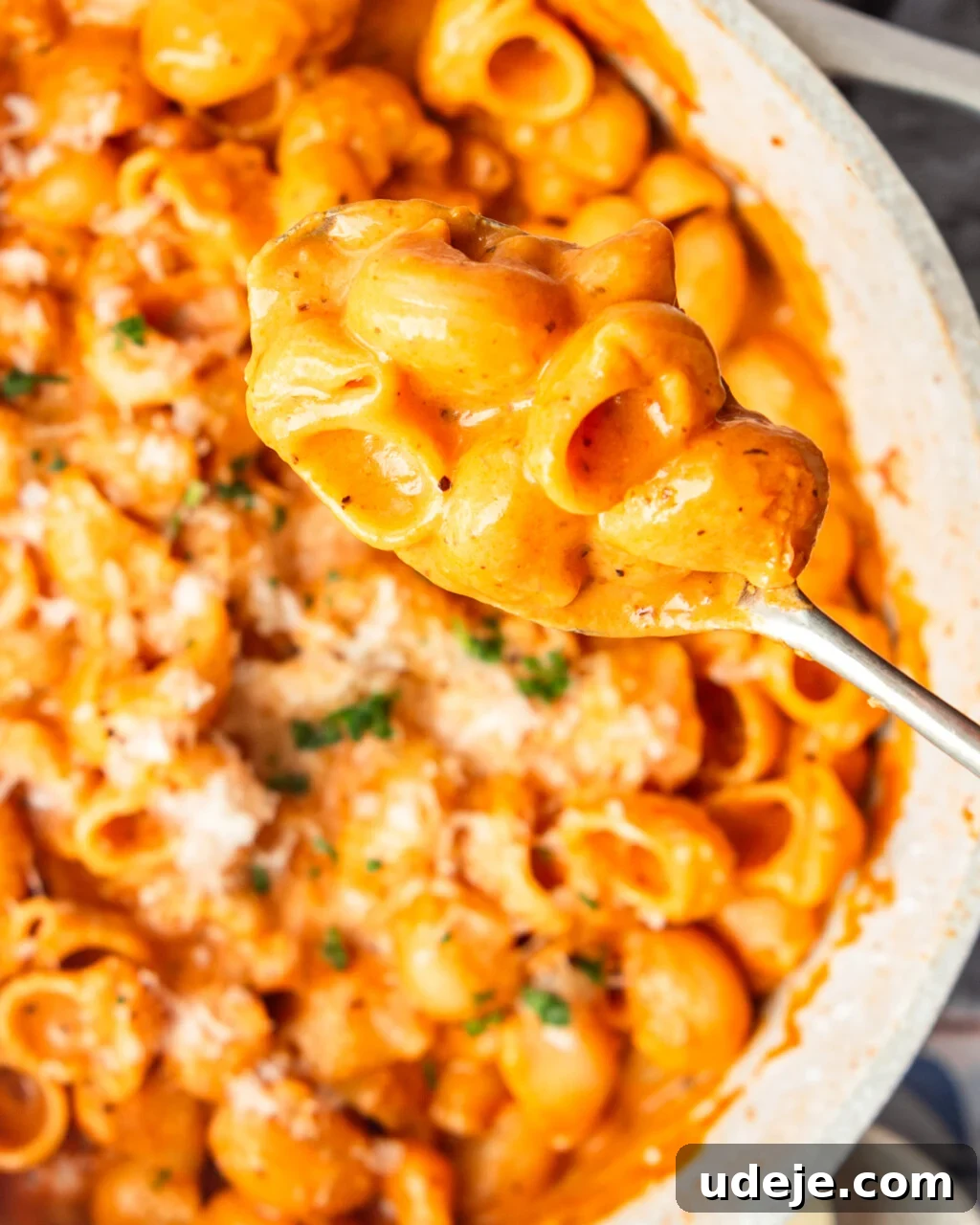 30-Minute One-Pot Creamy Pink Pasta 3 White pot with shell pasta in a light orange sauce and parmesan and parsley sprinkled with a metal serving spoon