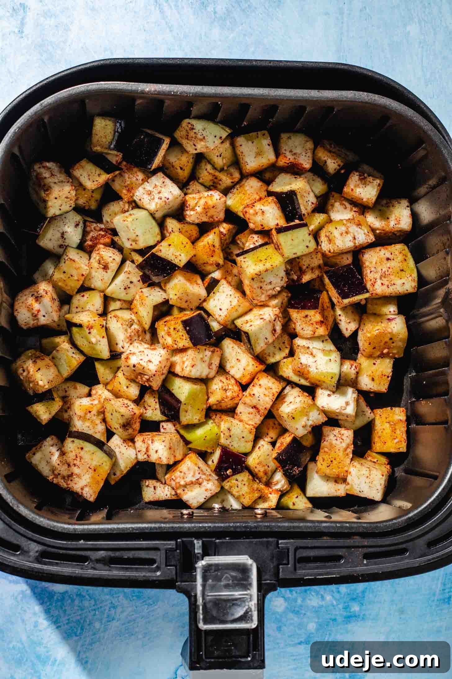 Mediterranean Eggplant Fatteh Delight 4 Seasoned eggplant cubes in an air fryer basket, ready for cooking.