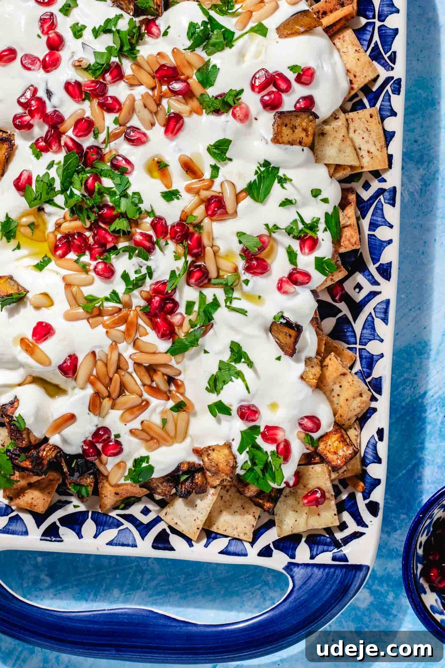Mediterranean Eggplant Fatteh Delight 10 Eggplant fatteh beautifully plated on a patterned blue plate with handles, ready to be enjoyed.