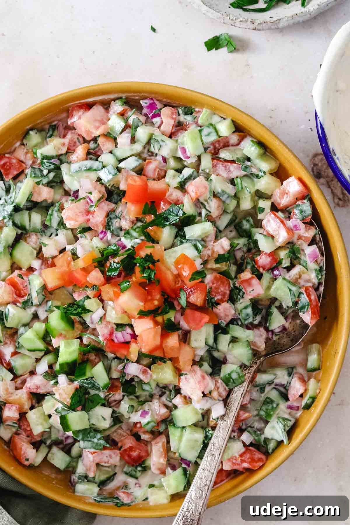 Effortless Skillet Tender Beef Shawarma 10 tahini salad served in a yellow shallow bowl with a spoon inside