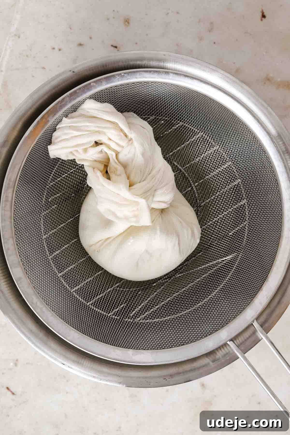 steel bowl with strainer with labneh tied in cheesecloth