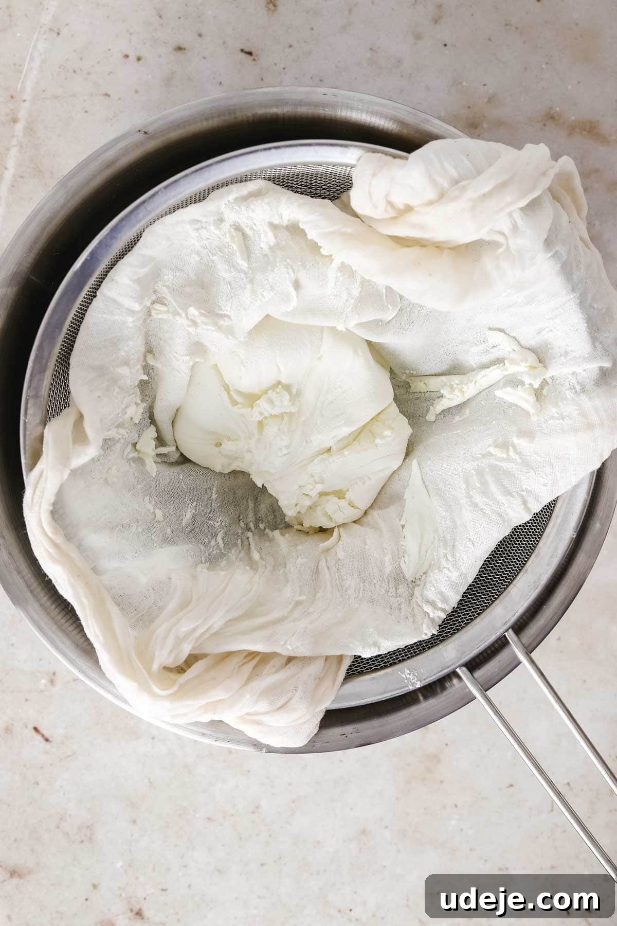 steel bowl with strainer with cheesecloth and labneh in the strainer