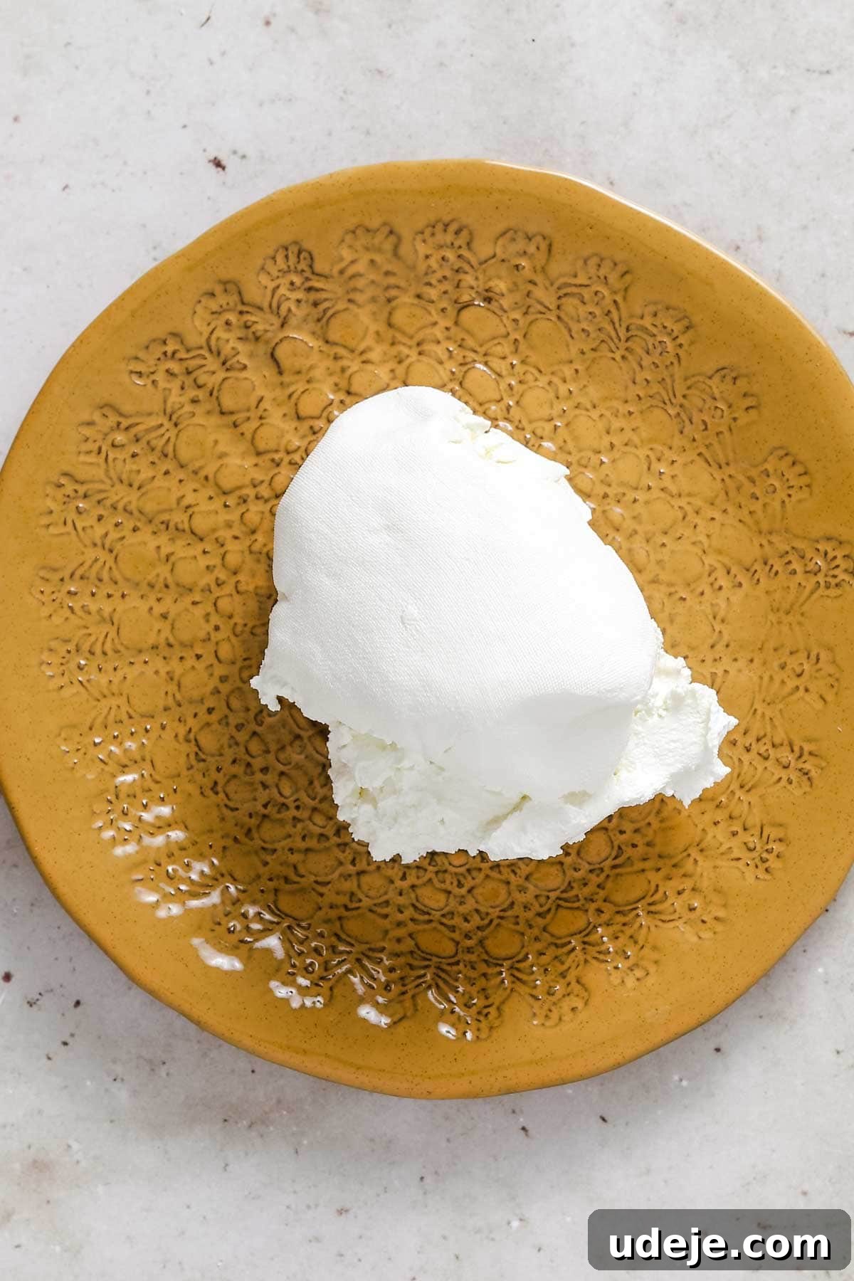 Mustard yellow plate with a scoop of labneh