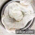 steel bowl with strainer with cheesecloth and labneh in the strainer