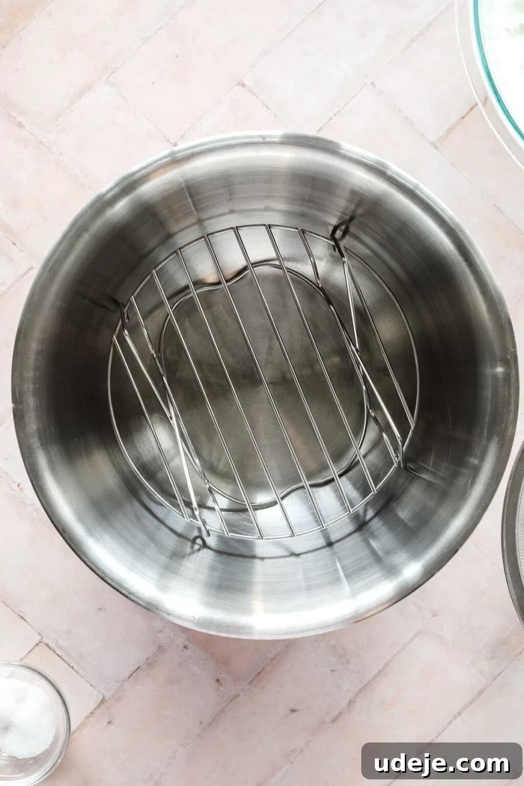 steel bowl with trivet inside, small glass bowl of salt and medium glass bowl of yogurt in corner, on a pink background