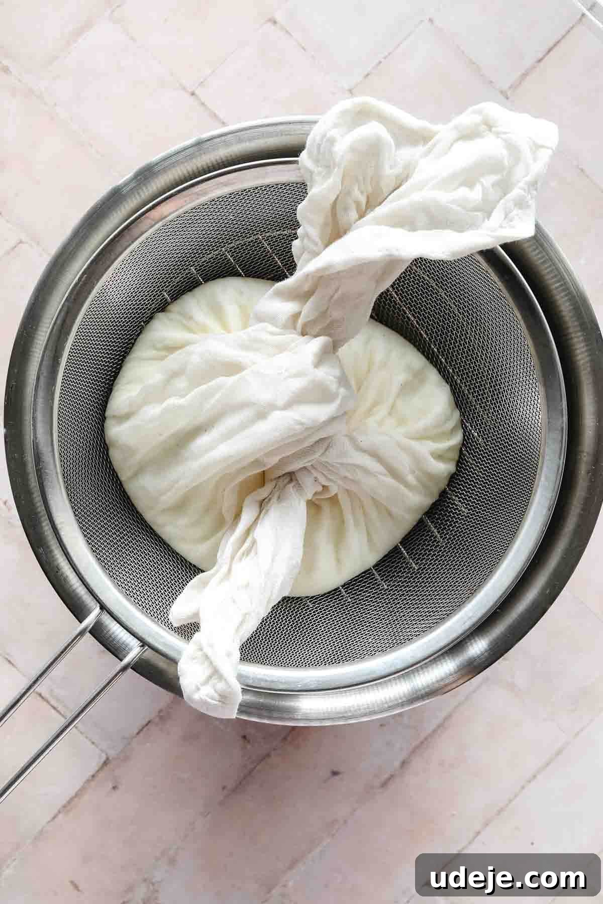 steel bowl with strainer with labneh tied in cheesecloth