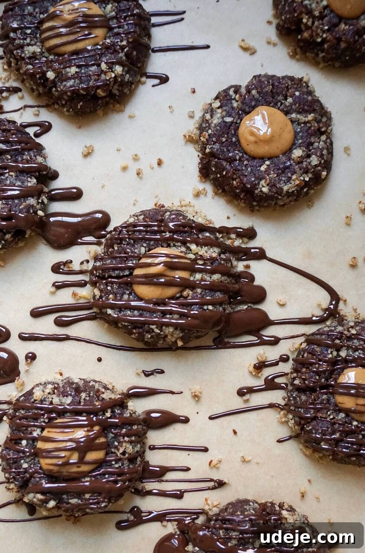 Indulgent No-Bake Vegan Gluten-Free Chocolate Turtles 2 No Bake Chocolate Turtle Cookies with a peanut butter center, topped with crushed pecans, and elegantly drizzled with melted chocolate.