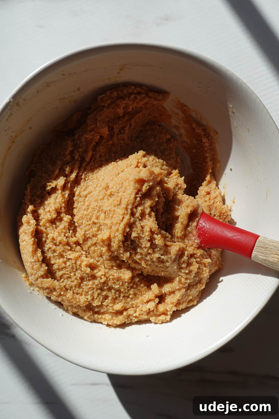 Simple Three Ingredient Vegan Gluten Free Peanut Butter Cookies 6 A bowl of peanut butter cookie dough being mixed, showcasing its smooth and pliable texture before shaping