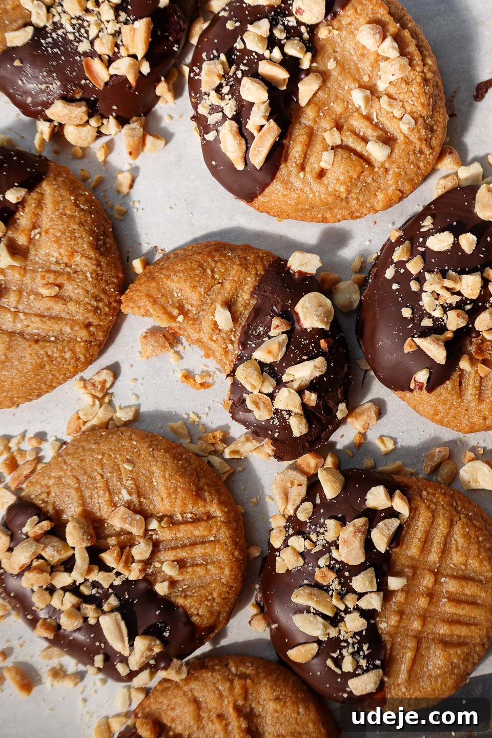 Simple Three Ingredient Vegan Gluten Free Peanut Butter Cookies 9 Overhead view of 3-ingredient peanut butter cookies half dipped in chocolate and sprinkled with chopped peanuts, ready to be enjoyed