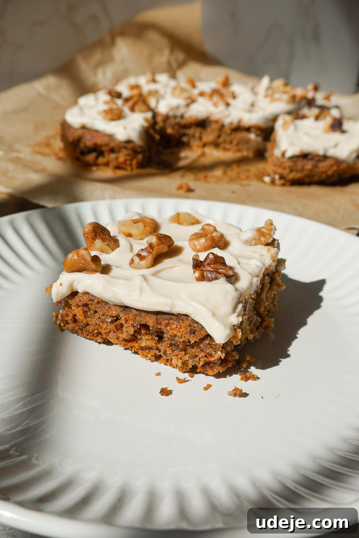 Wholesome Vegan Gluten Free Carrot Cake 5 slice of healthy carrot cake on a plate and topped with vegan cream cheese frosting and chopped walnuts