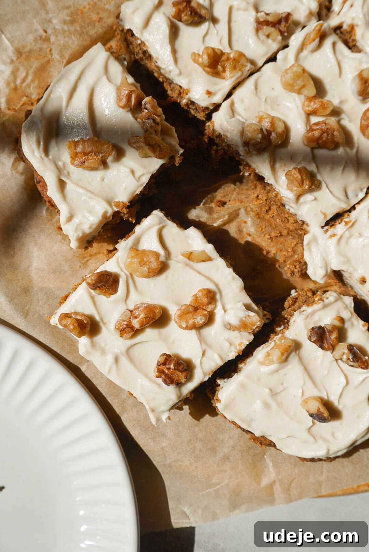 Wholesome Vegan Gluten Free Carrot Cake 6 overhead shot of healthy carrot cake sliced and topped with vegan cream cheese frosting and chopped walnuts
