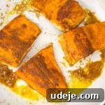 A light-colored skillet with pieces of fish that have been perfectly seared to a golden-brown, ready for the next step in the cooking process.