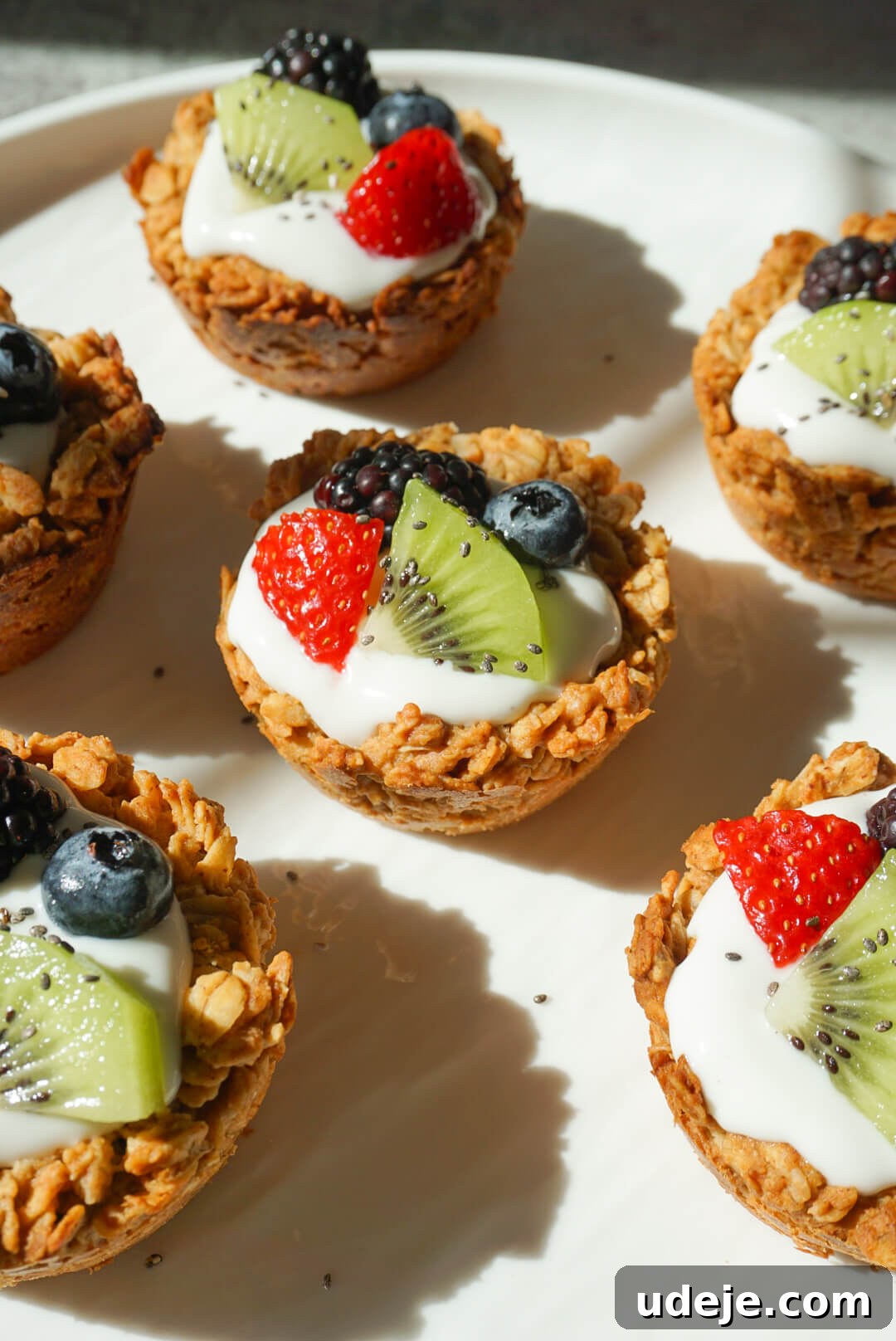 Effortless Granola Yogurt Treats 2 Freshly prepared granola yogurt cups topped with an abundance of colorful mixed berries and a sprinkle of chia seeds, presented beautifully for a healthy breakfast.