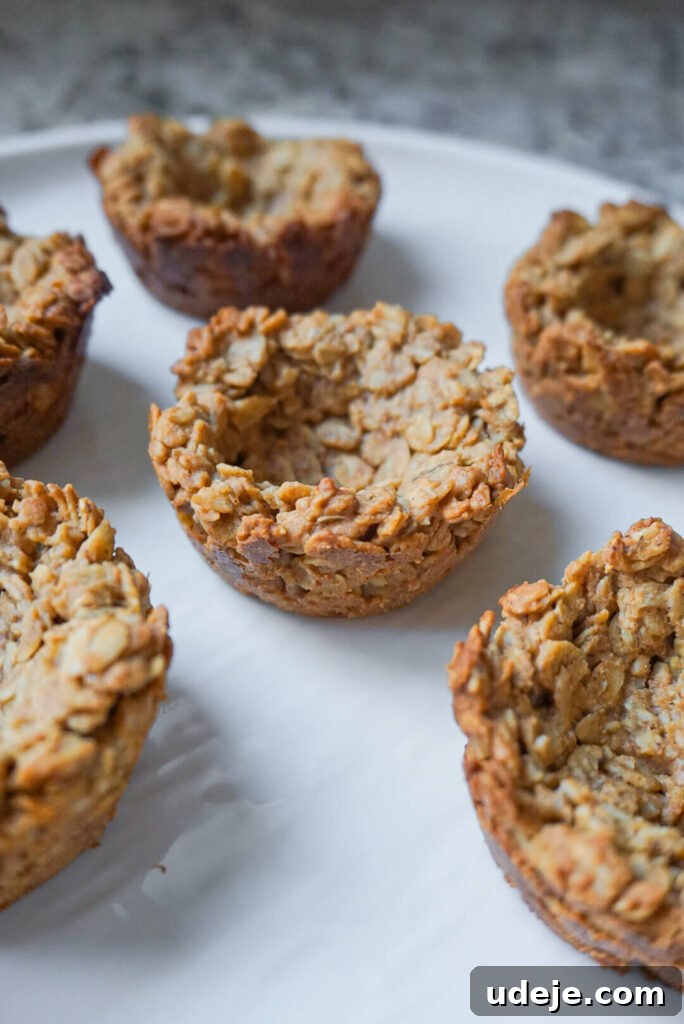 Effortless Granola Yogurt Treats 5 A muffin tin with granola mixture pressed into six cavities, showing the distinct well created in the center of each cup, ready for baking.